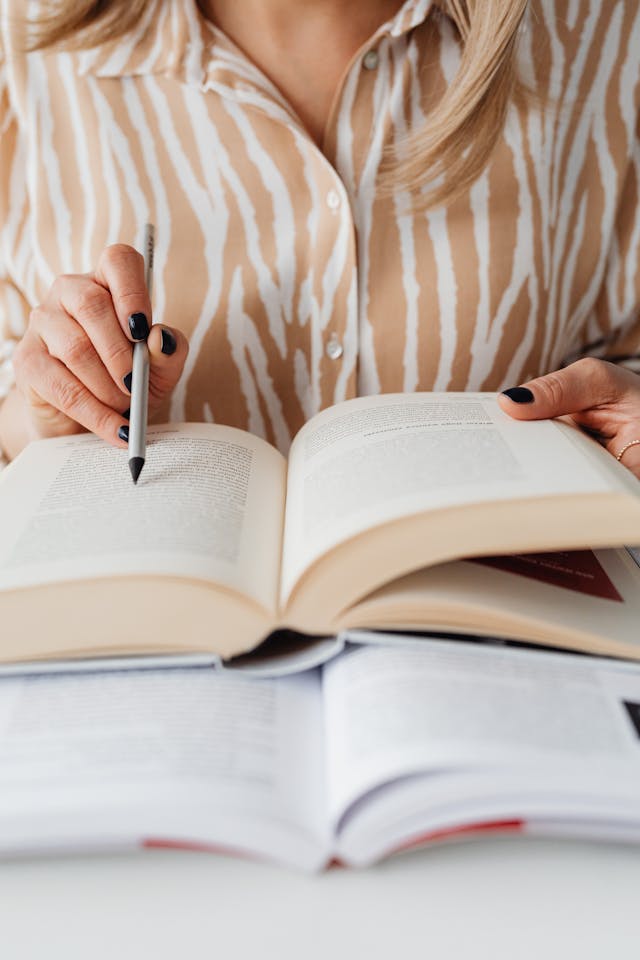 author reading a book and pointing at it with a pen